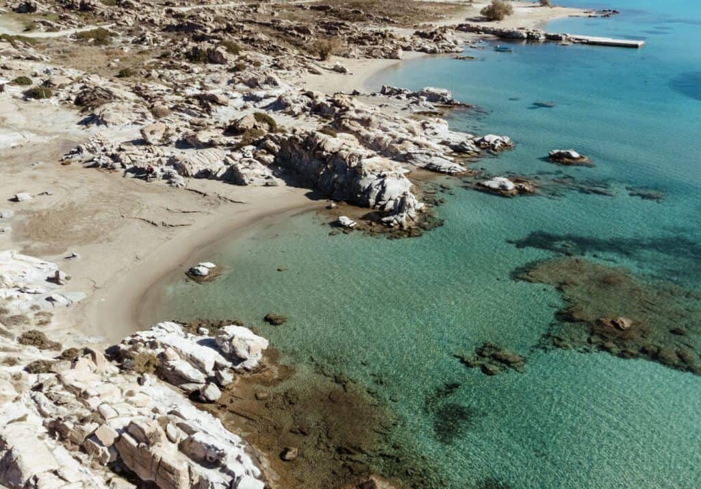 Aerial View of a calm and secluded day at Kolymbithres Beach, with turquoise water and rock formations along the shoreline