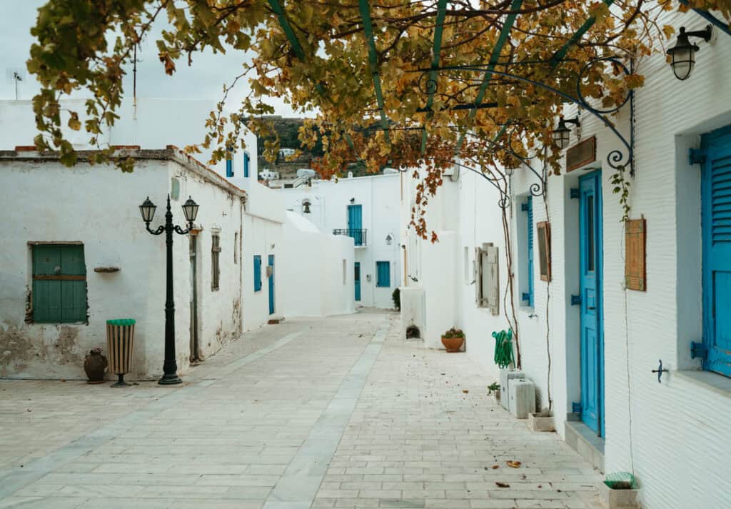 view of a beautiful street in Leftkes, Paros. The cobblestone streets are lined with white buildings accented with light blue doorframes