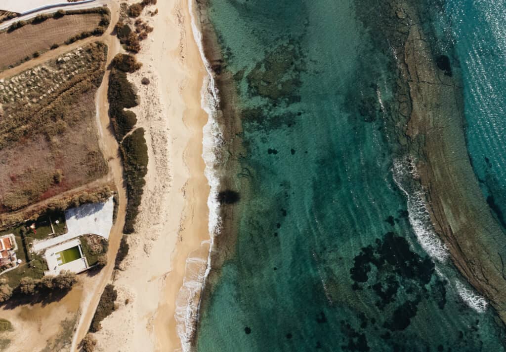 aerial view of Plaka Beach in Naxos, Greece. The water is incredibly clear and blue