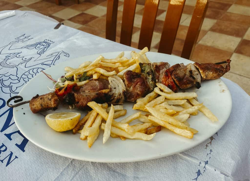 a mixed meat skewer with fries on a plate at Gorgona Greek Taverna in Naxos
