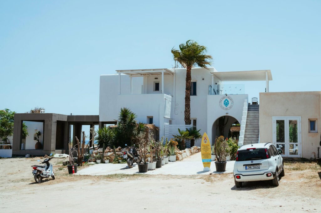 Surf school and rental shop near Golden Beach Paros with white Cycladic architecture and palm trees.