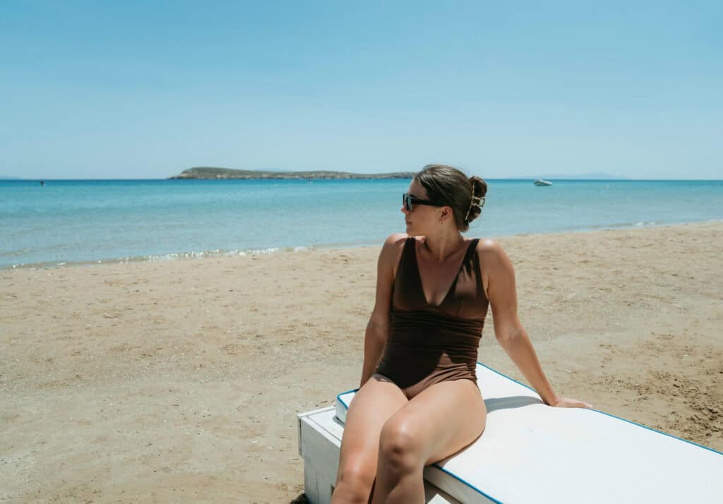 Sarah relaxing on a beach lounger at Golden Beach Paros with calm turquoise water in the background.