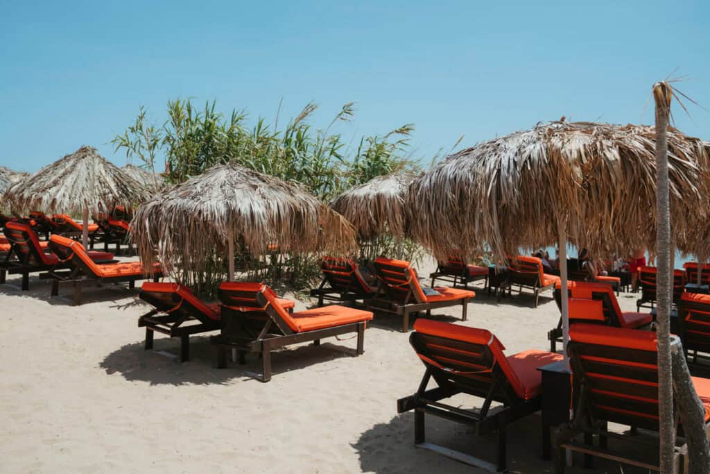 Thatched umbrellas and bright orange loungers lined up on the sand at Golden Beach Paros.