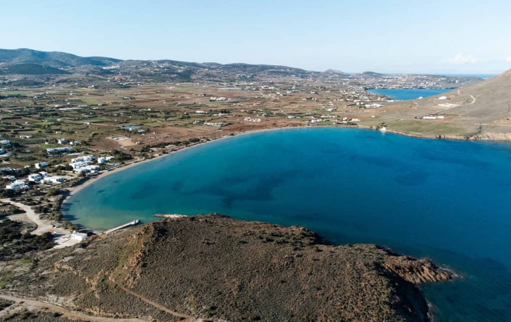 An drone view of Molos Beach. You can see a mountain in the foreground of the photo and the entire stretch of Molos Beach and the turquoise blue bay. 