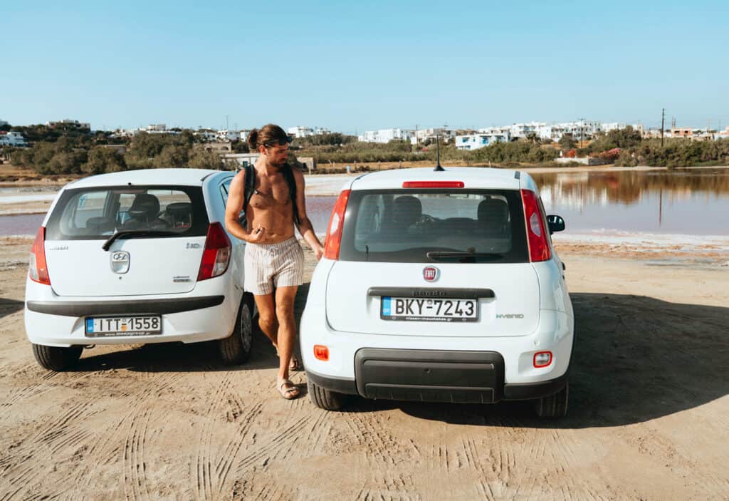 Caleb in swim trunks walking our rental car near a beach in Naxos