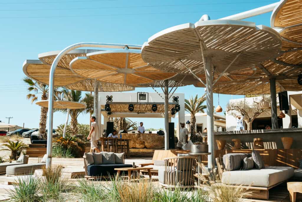Stylish open-air bar and DJ booth at Marcello Beach Paros, featuring modern design, shaded lounge areas, and a vibrant beach club atmosphere.