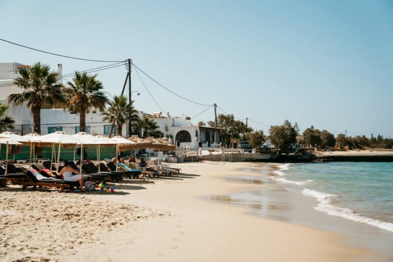 Relaxed scene at one of the best hotels in Agia Anna, Naxos with sunbathers lounging under umbrellas.
